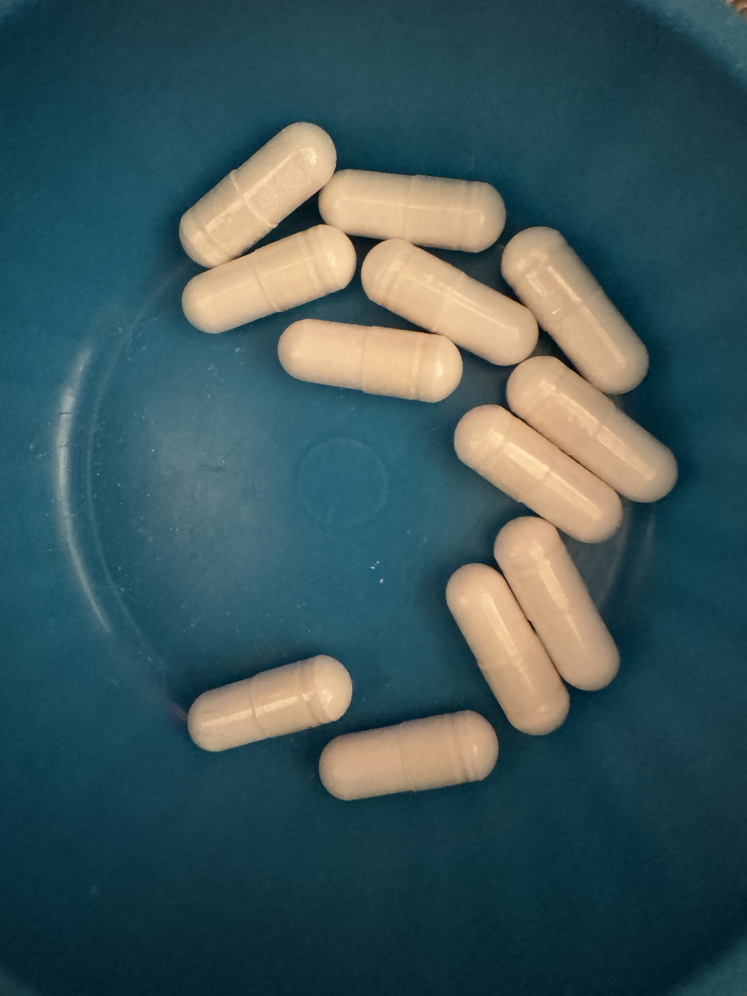 The bottom of a blue bowl with white magnesium capsules.